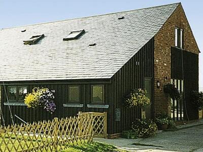 a black house with a black roof at Owl Barn in Burmarsh