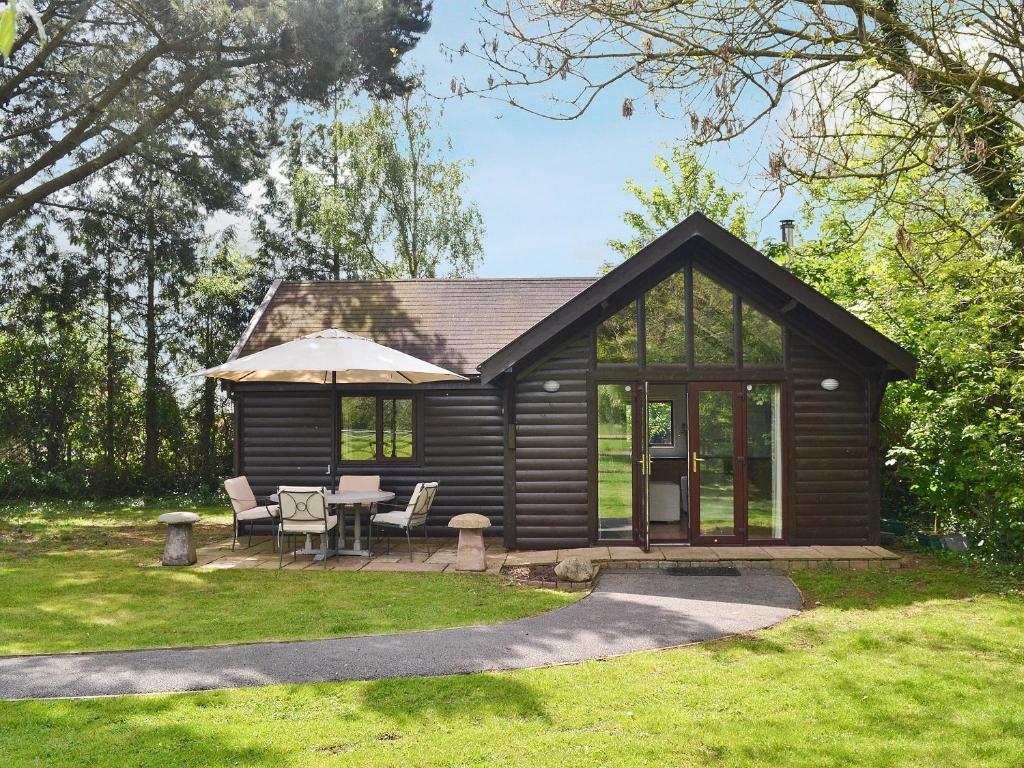 a log cabin with a table and an umbrella at Strawberry Lodge in Cheddar
