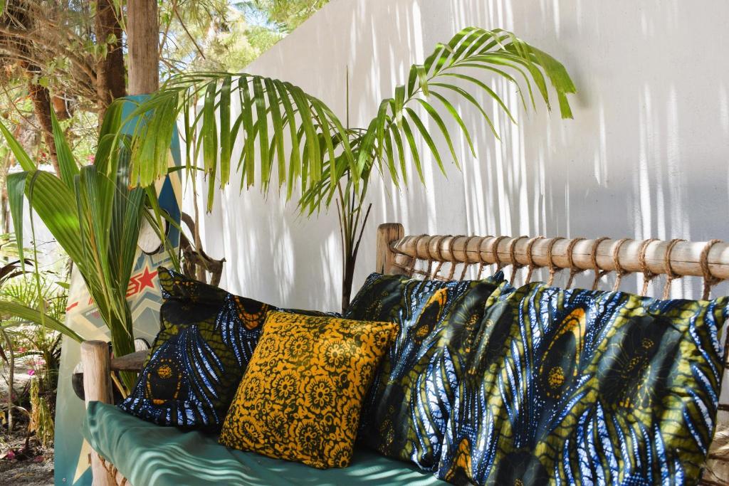 un canapé avec des oreillers assis à côté d'une plante dans l'établissement Maryam Garden Apartments & Villa, à Bwejuu