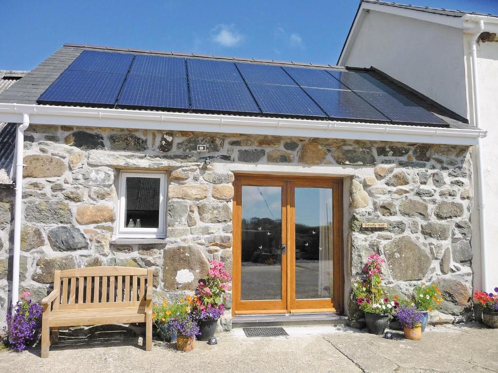 a stone house with solar panels on the roof at Beudy Isaf in Llangybi