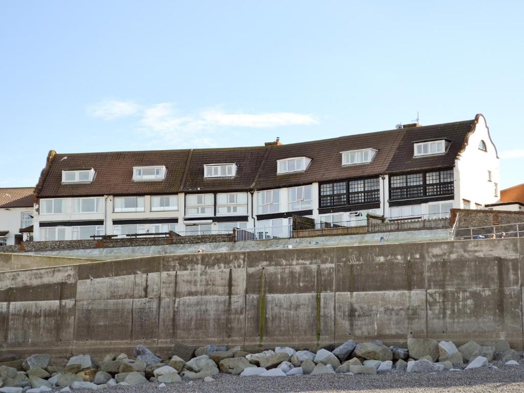 a building behind a wall with rocks in front of it at Turnstone Cottage in Sheringham
