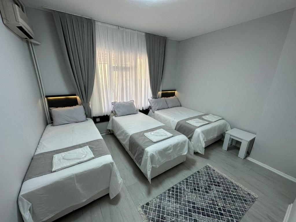 a hotel room with two beds and a window at Otel NİL FIRAT in Bursa