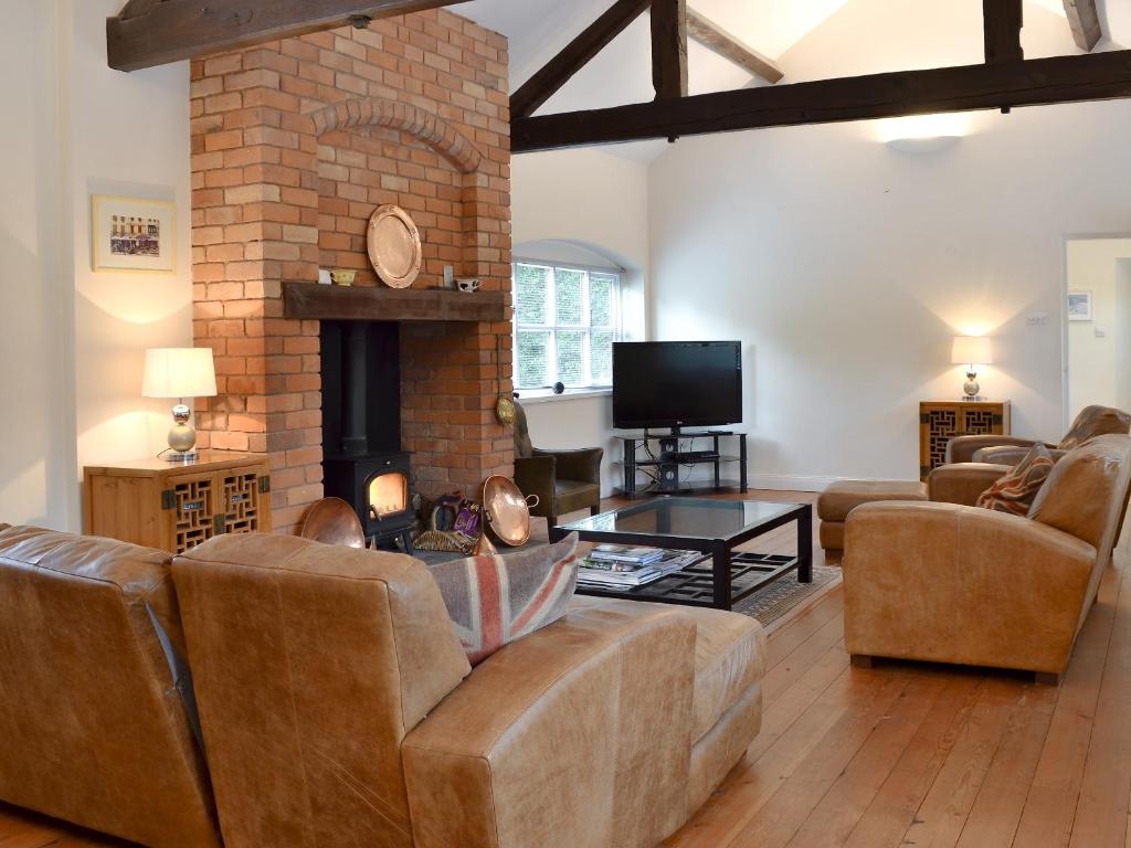 ein Wohnzimmer mit einem Sofa und einem Kamin in der Unterkunft The Old Stables in Standon