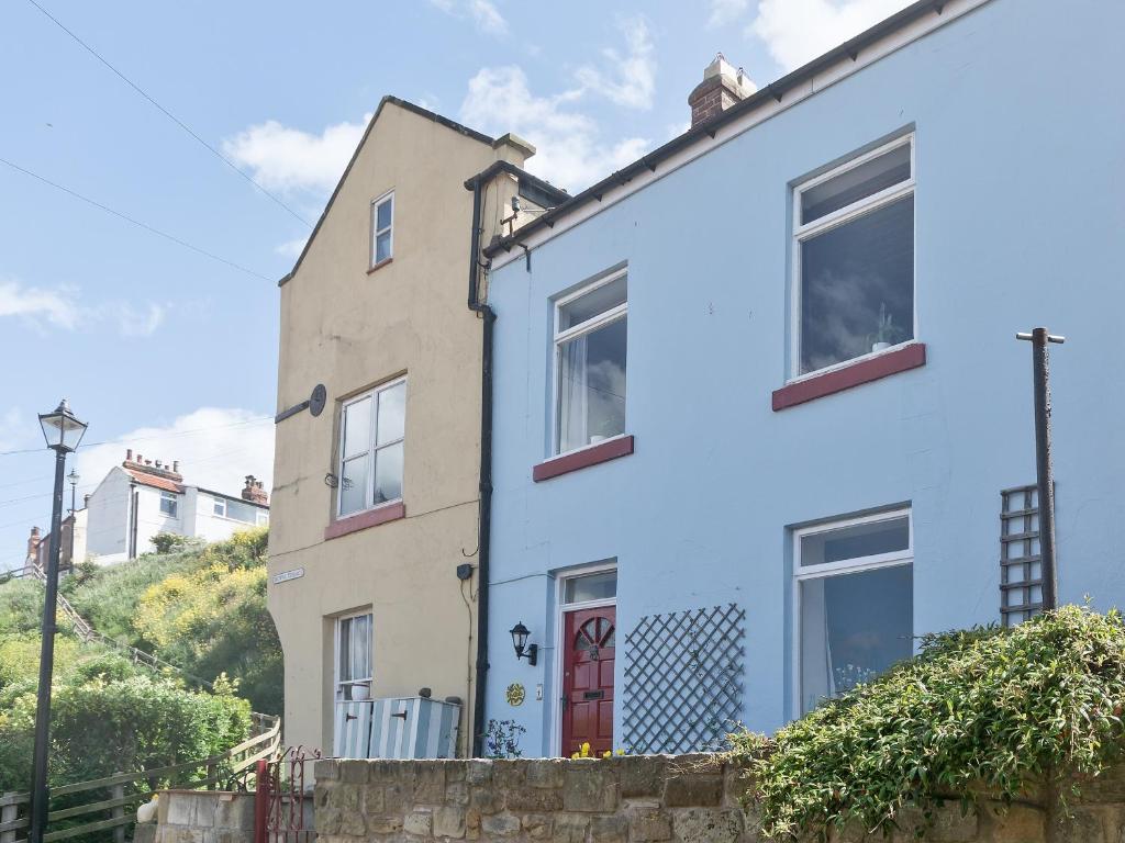 a house with blue paint on the side of it at Tinakori in Staithes