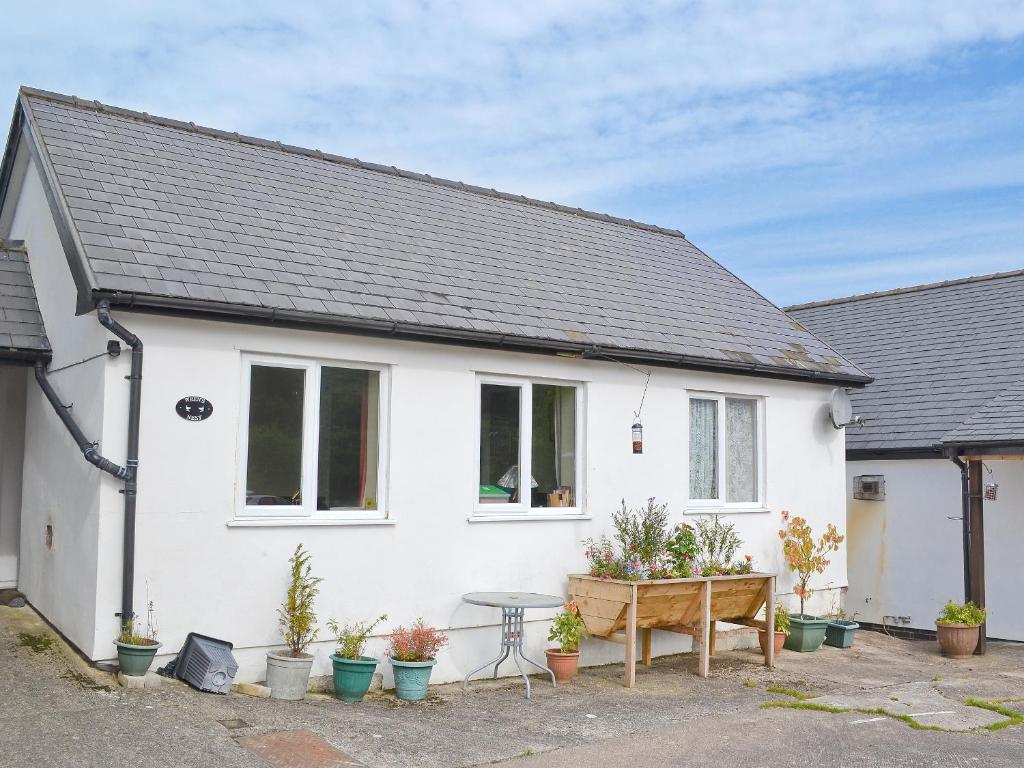 een wit huis met een tafel en potplanten bij Wrens Nest in Llanfair Caereinion