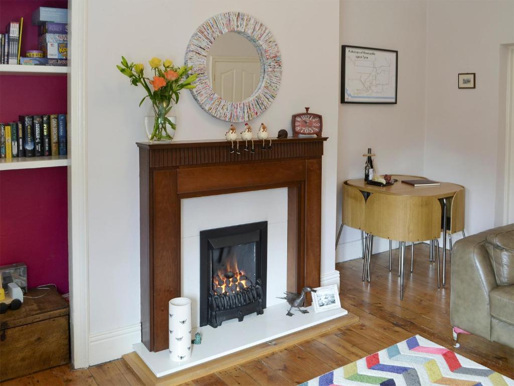 a living room with a fireplace and a table at Naters Apartment in Cullercoats