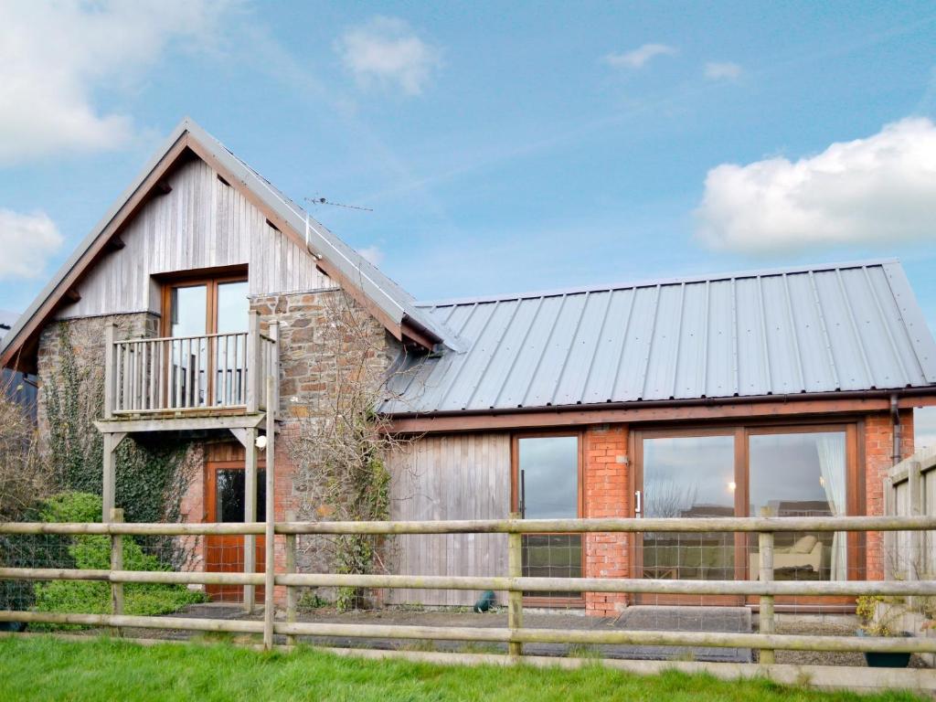 a barn conversion with a metal roof and a wooden fence at Torridge in Great Torrington