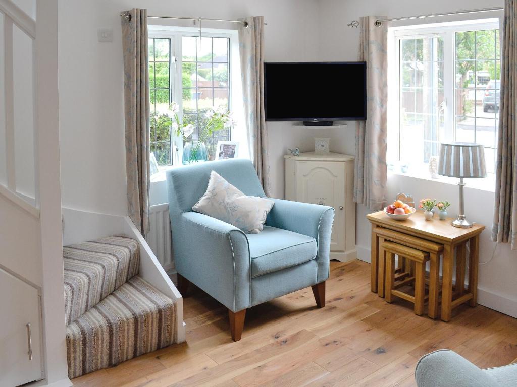 a living room with a blue chair and a television at Little Willows in Bradenham