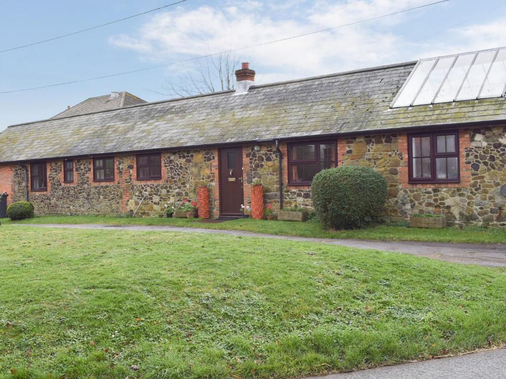 an old stone house with a grass yard in front of it at The Blacksmith Shop in Shorwell