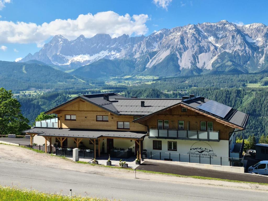 a large wooden building with mountains in the background at Ferienwohnung Talbach in Schladming