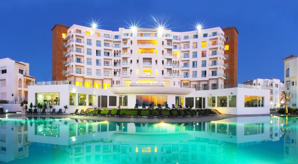 ein großes weißes Gebäude mit einem Pool davor in der Unterkunft Grand Mogador Sea View & Spa in Tangier