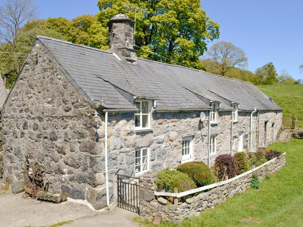 an old stone house with a black roof at Hen Hafod in Llanfor