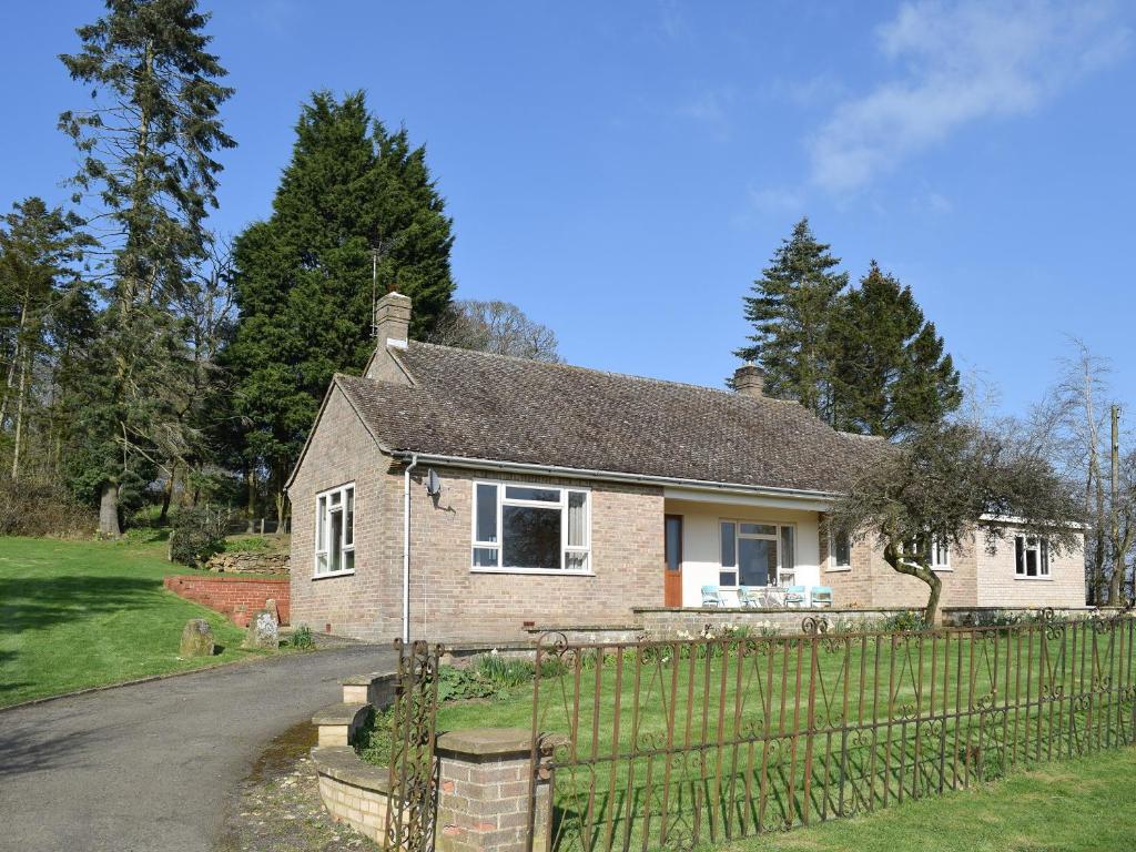 a brick house with a fence in a yard at Roundhill in Eydon