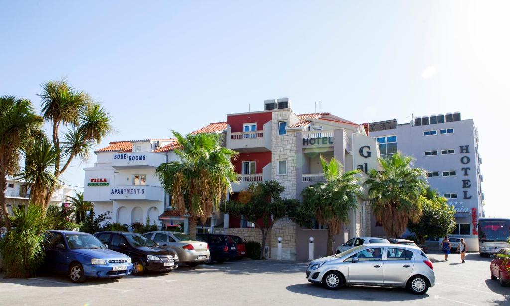 un estacionamiento con autos estacionados frente a un edificio en Hotel Gala Split, en Podstrana