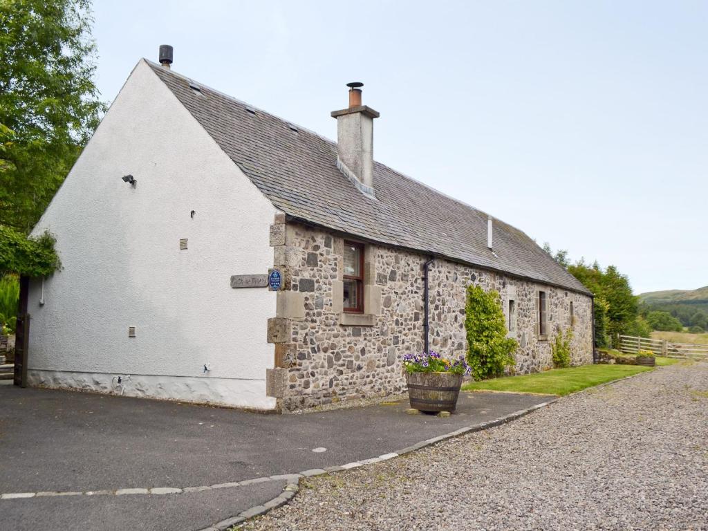 an old stone building with a bucket of flowers in front of it at Old Stones in Glendevon