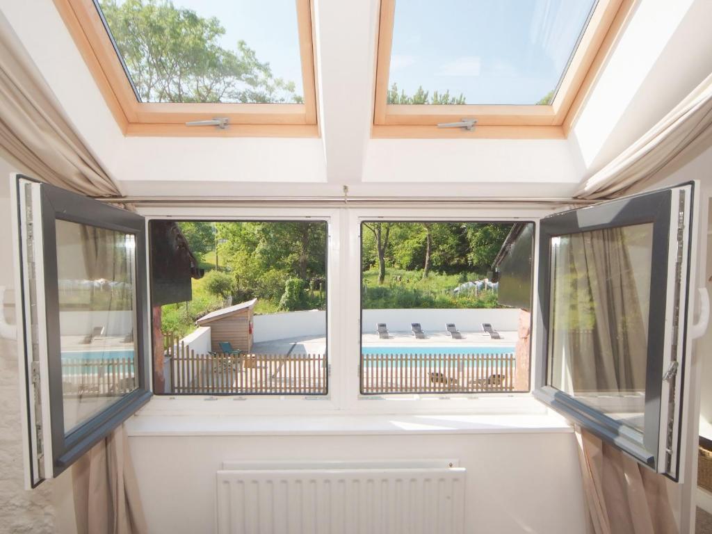 MarldonにあるIvy Cottage - 28150のプールの景色を望む窓2つが備わる客室です。