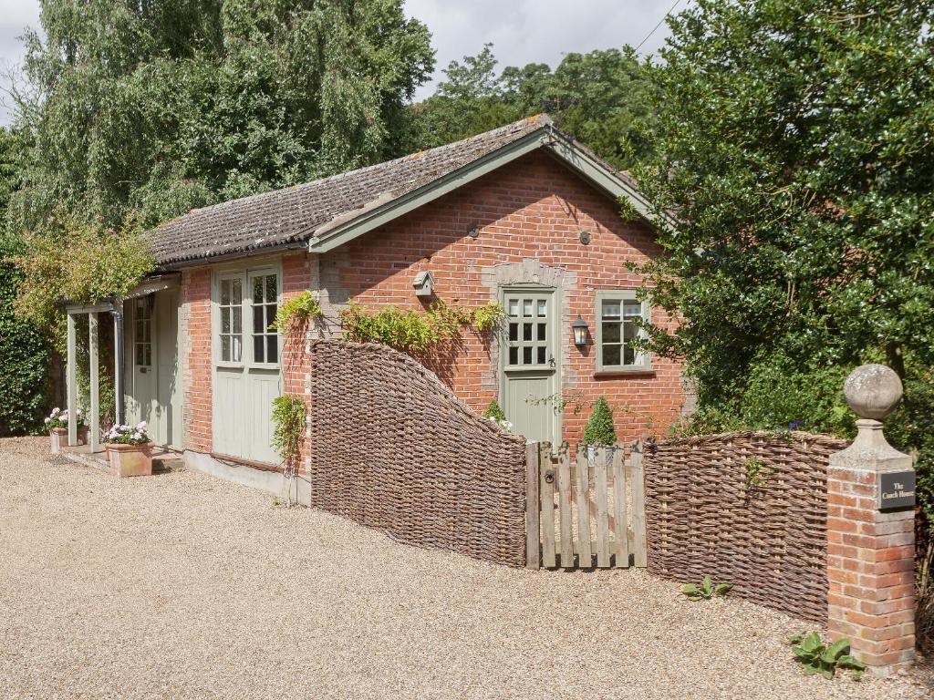 a brick house with a fence in front of it at The Coach House in Tattingstone