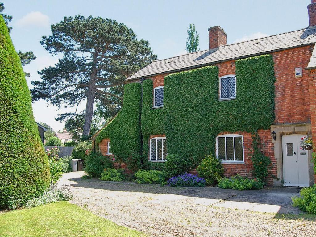 uma casa coberta de hera com uma porta branca em Park House em Harlaxton