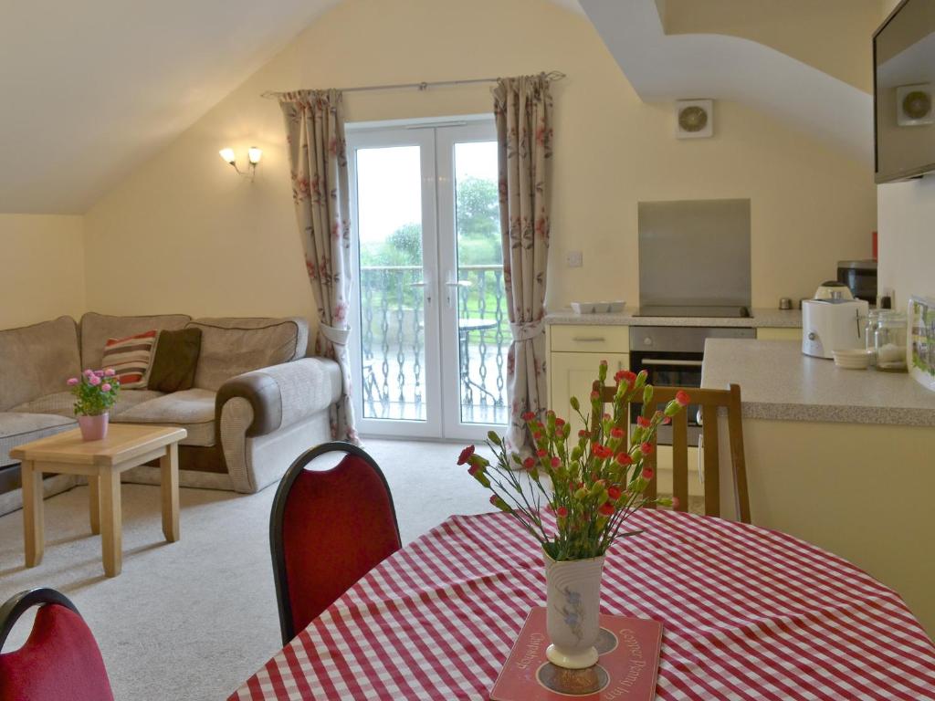 eine Küche und ein Wohnzimmer mit einem Tisch und einem roten Tischtuch in der Unterkunft Hare Lodge in Lamerton