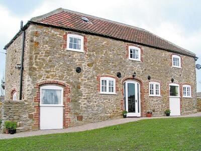 uma casa de tijolos com portas brancas e um campo de relva em The Granary Barn - 25589 em North Willingham