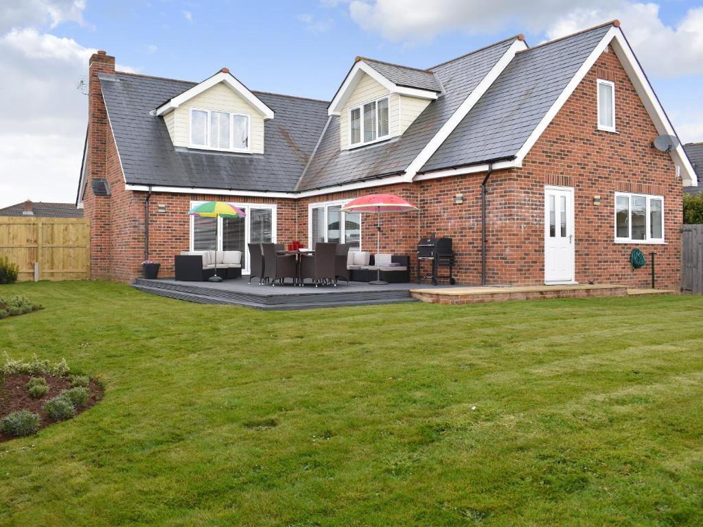 a brick house with a patio with tables and umbrellas at Grove Cottage in Newchurch