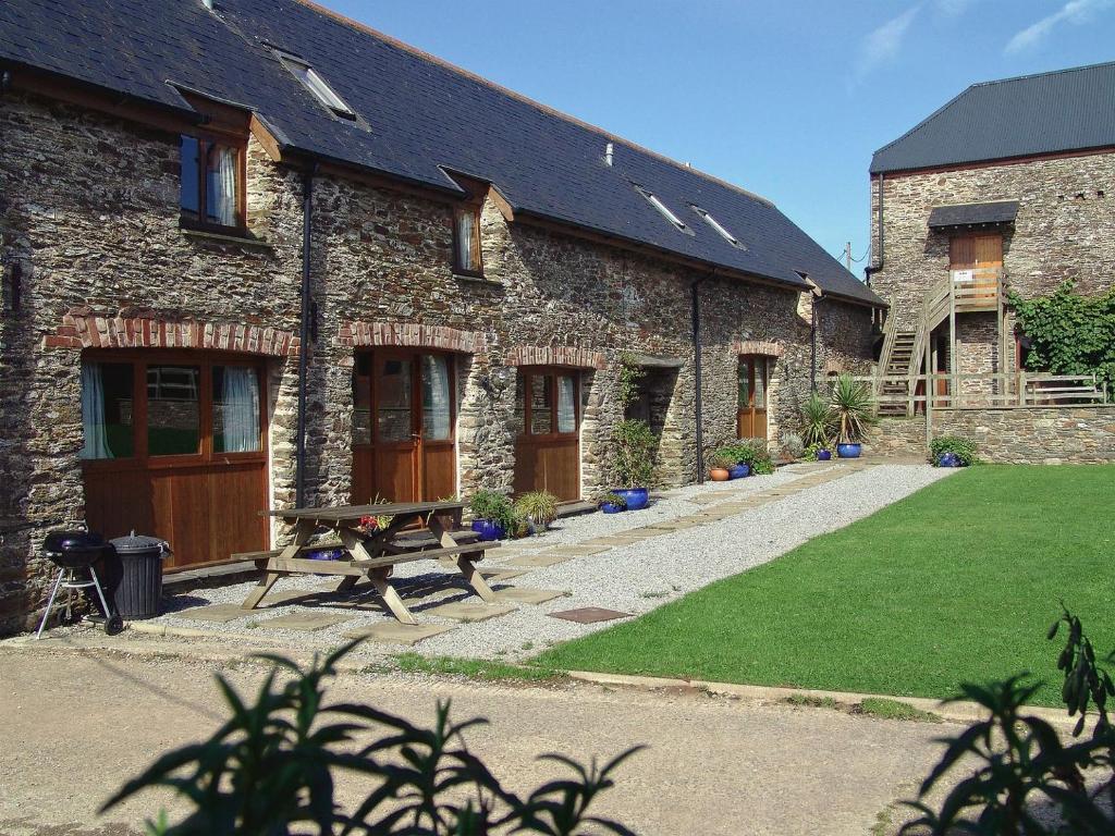 a stone building with a bench in front of it at Mad Nelly Cottage in Moreleigh