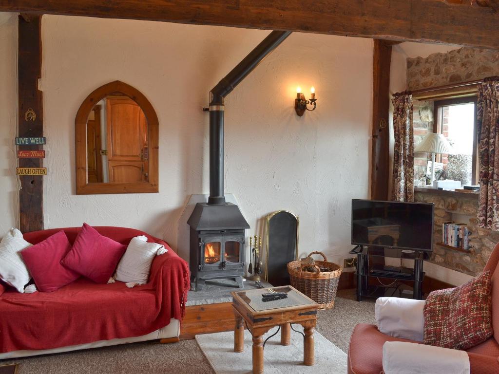 a living room with a red couch and a wood stove at Brandy's in Colyton