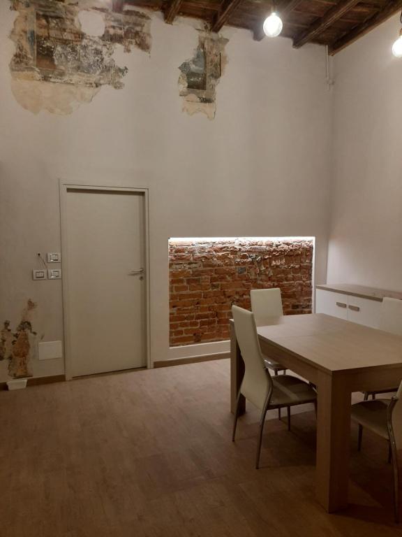 um quarto com uma mesa e cadeiras e uma parede de tijolos em Il Garibaldi em Savigliano