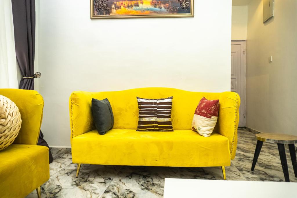 a yellow couch with pillows on it in a living room at Spectacular 3/4-Bed-Apt With 24hrs Power And FAST Wi-Fi in Amuwo