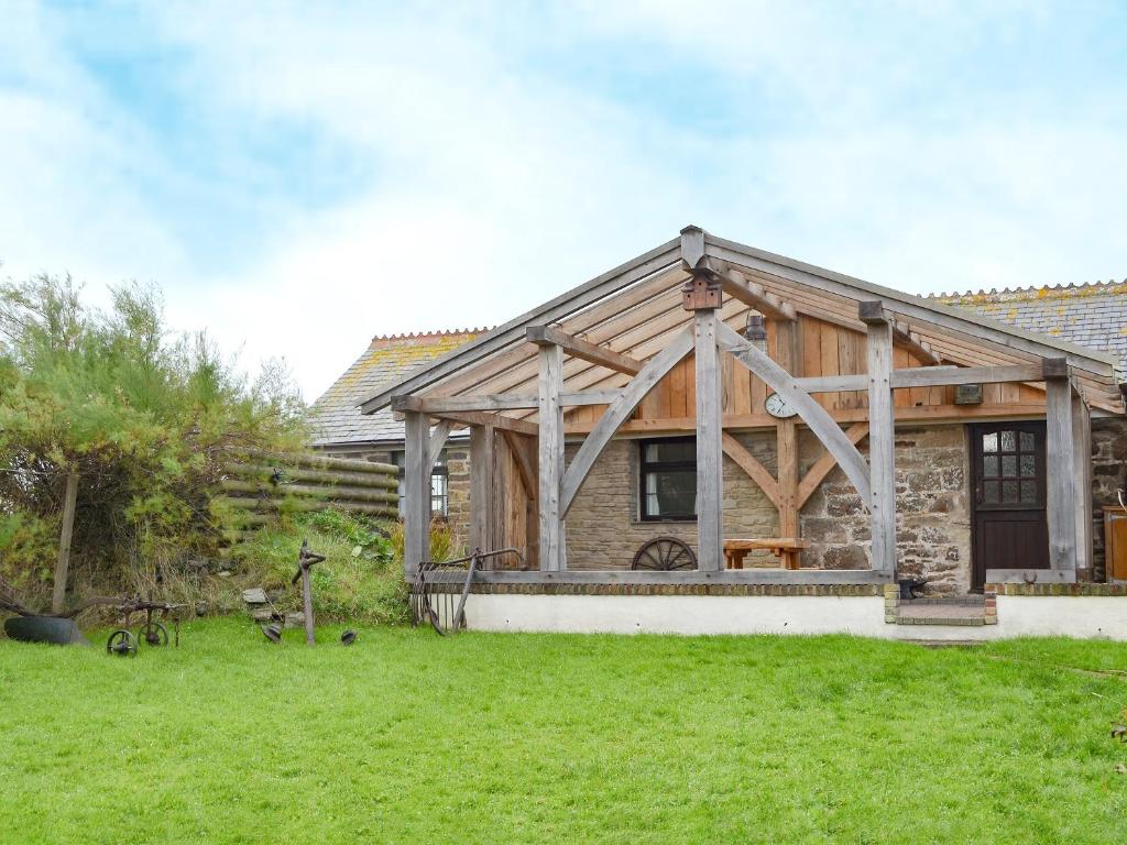 uma casa de madeira com um relvado verde em frente em Horseshoe Cottage -31299 em Holywell Bay