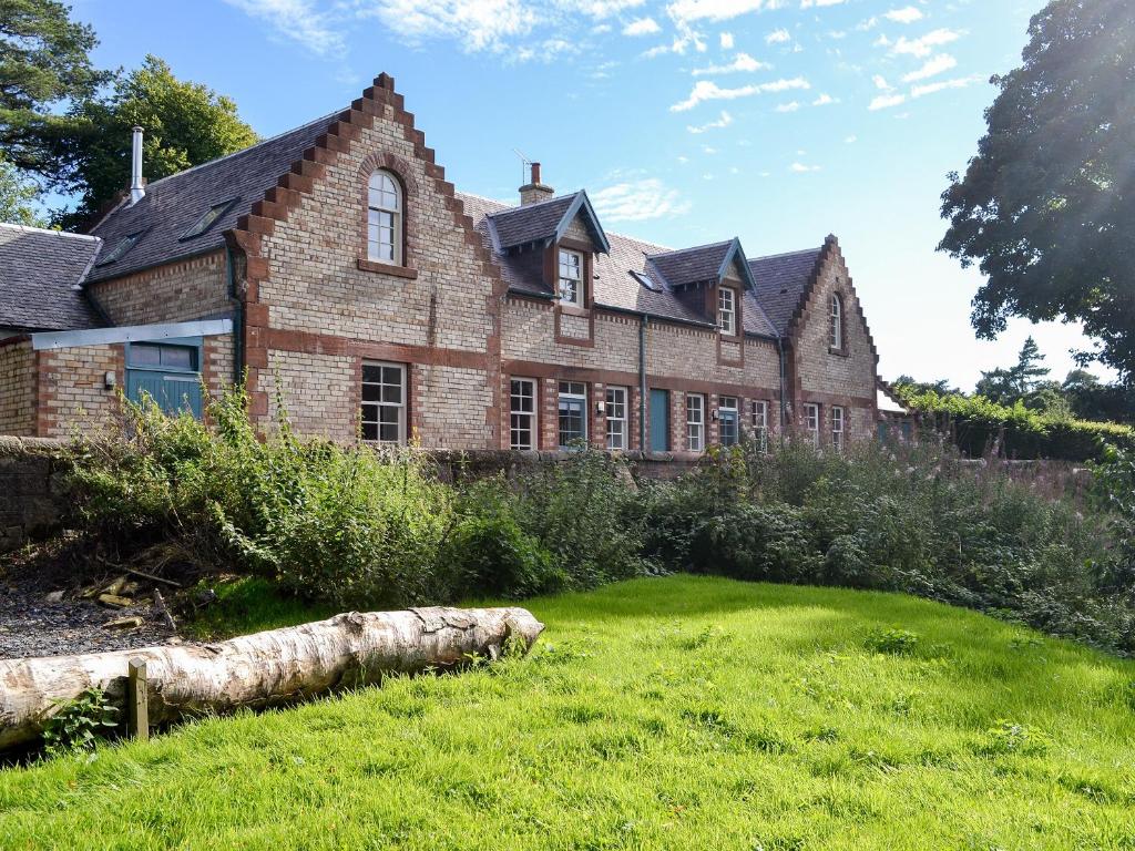 an old brick house with a lawn in front of it at One The Stables in Dalrymple