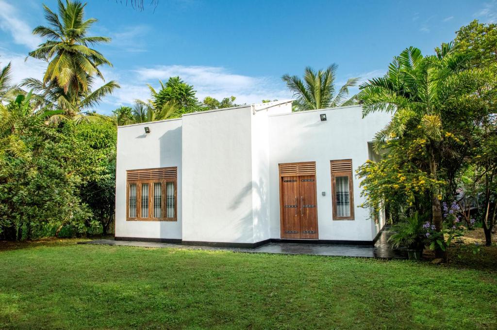 Casa blanca con puertas marrones y patio en Villa 146 Dickwella, en Batigama