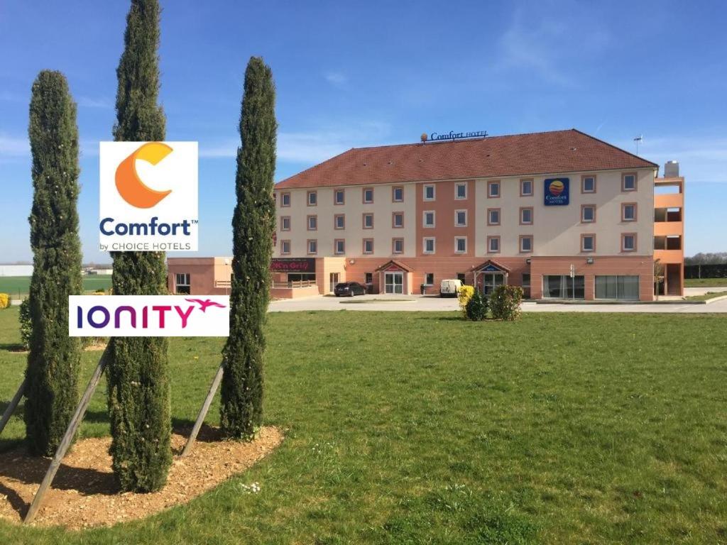um hotel com uma placa em frente a um edifício em Comfort Hotel Dijon Sud - 21600 LONGVIC em Dijon