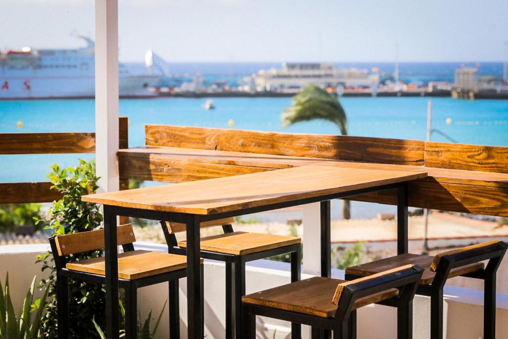 una mesa de madera y sillas en un balcón con vistas al océano en Ocean Nomads Coworking, en Arona