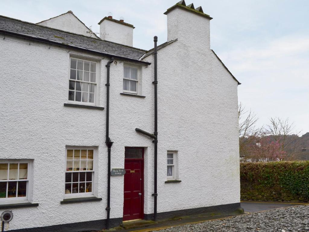 a white house with a red door on a street at Daisy Bank Cottage in Bowness-on-Windermere