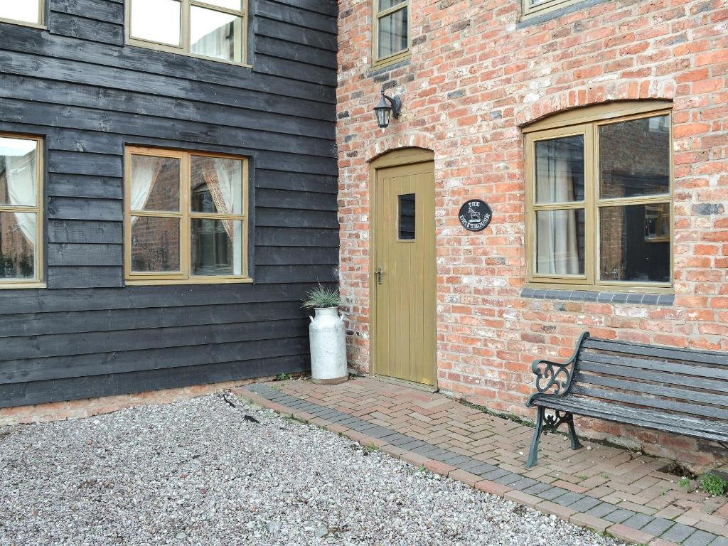 a wooden bench next to a brick building with a door at The Drift House in Coddington