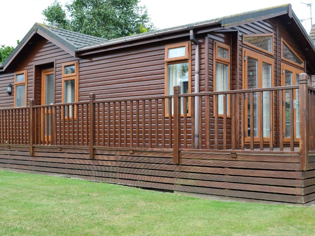 a large wooden cabin with a large deck at Kingfisher Lodge in Gorleston-on-Sea
