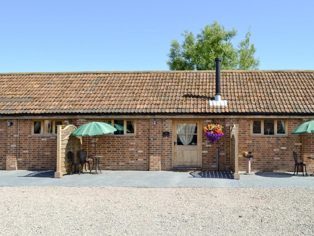 a brick building with a table and a green umbrella at The Cow Shed in Arlingham
