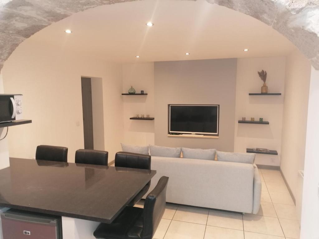 a living room with a table and a tv on a wall at Appartement paisible entre terre et mer in Cabrières