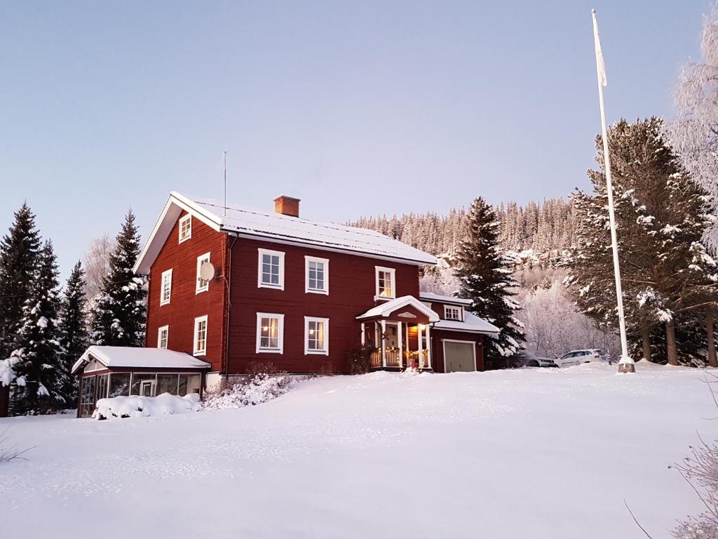 una gran casa roja con nieve delante en Backens Fjällboende, en Tännäs