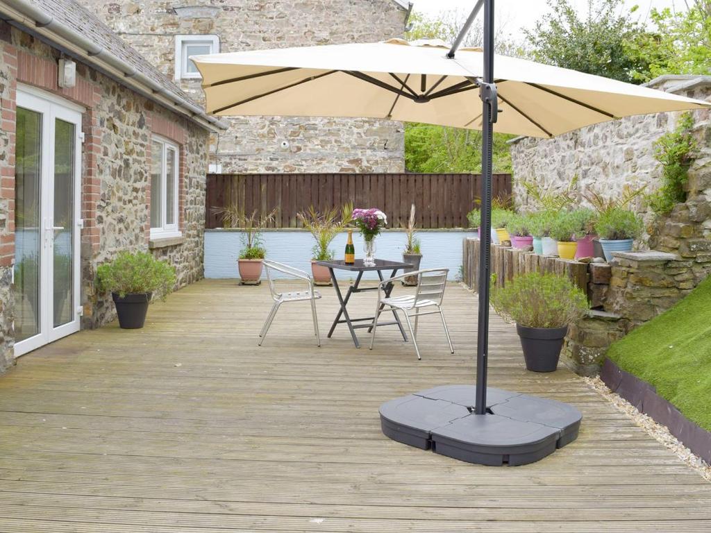 a patio with an umbrella and a table and chairs at Llwynbedw - 28464 in Cardigan