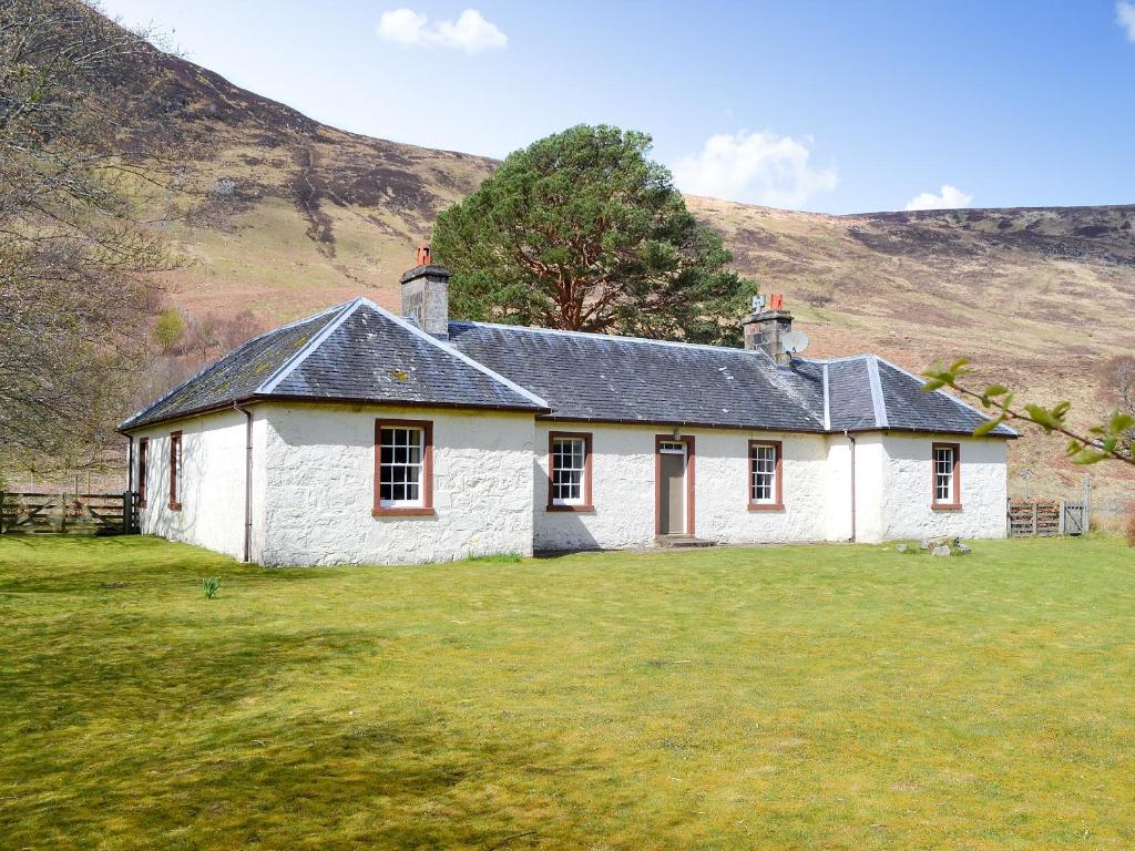 a white stone house with a hill in the background at Old West Manse in Bridgend