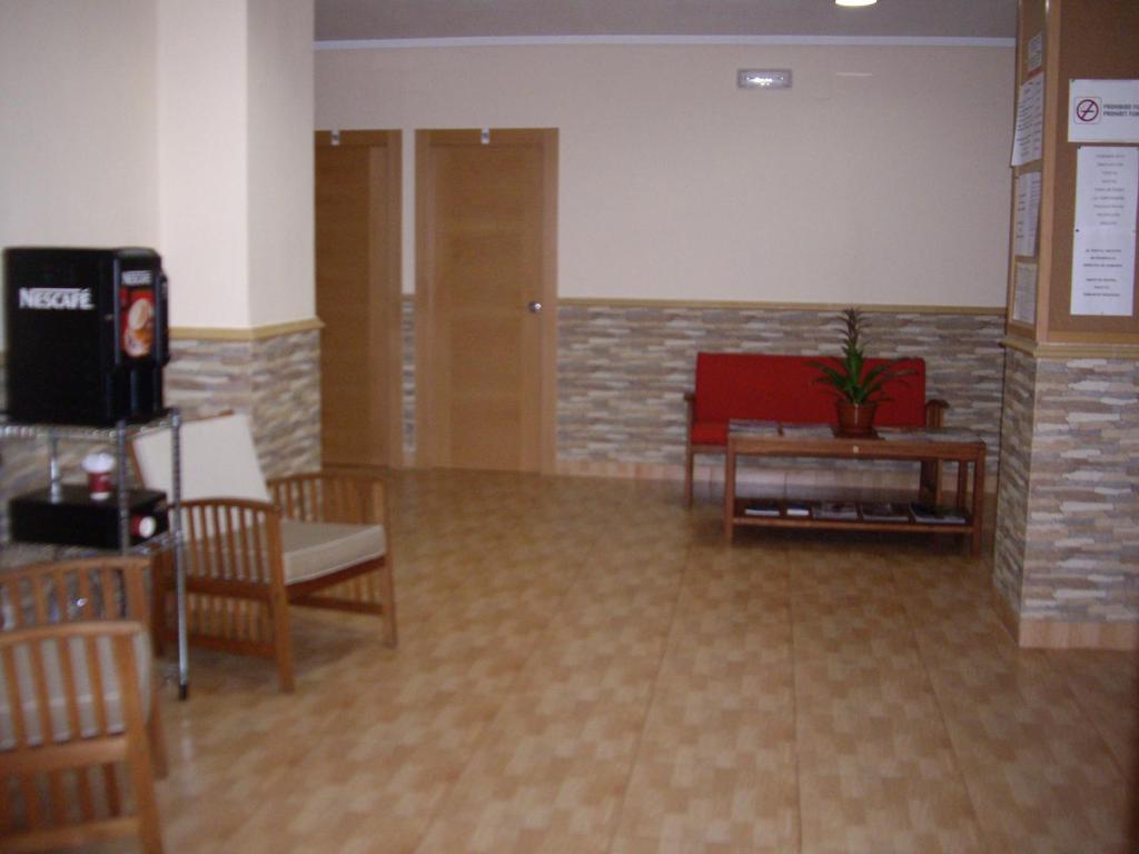 a waiting room with a red couch and chairs at Hostal Abastos in Valencia