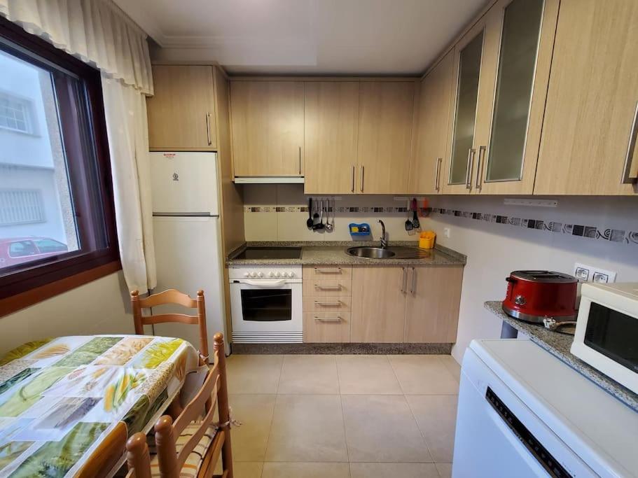 uma cozinha com armários de madeira e electrodomésticos brancos em Acogedor apartamento en Silgar em Sanxenxo