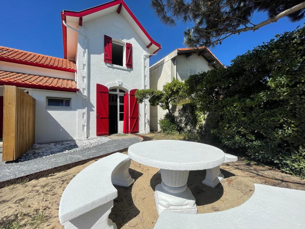 une table blanche devant une maison dans l'établissement Bocage 1, à Mimizan