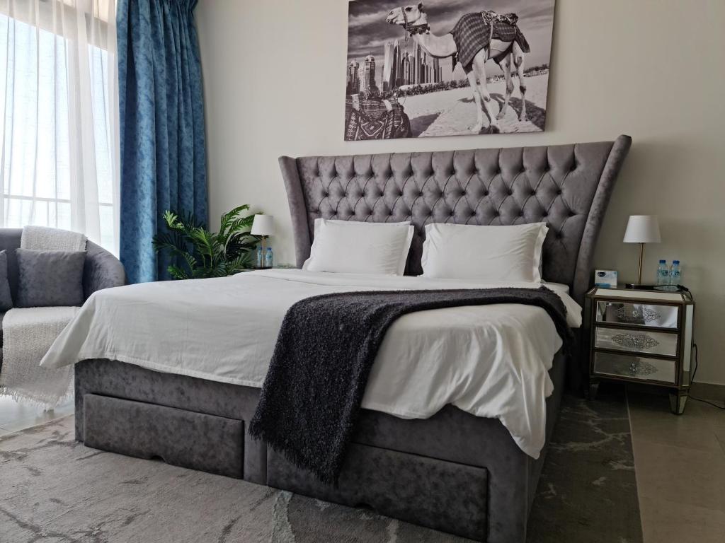 a bedroom with a large bed with a gray headboard at Cozy Furnished Studio in Abu Dhabi