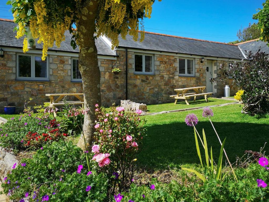 a stone house with a bench and flowers in front of it at Oak Barn in Porthtowan