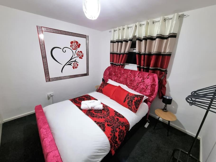 a bedroom with a bed with a red and white comforter at *C.sani* Setup for your most relaxed & amazing stay + Free Parking + Free Fast WiFi * in Leeds