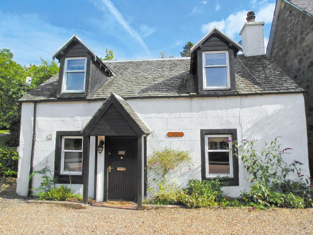 Casa blanca con puerta y ventanas negras en Craigdarroch Cottage en Strathyre