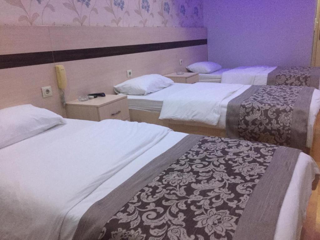 a hotel room with three beds with white sheets at burak otel in Unye